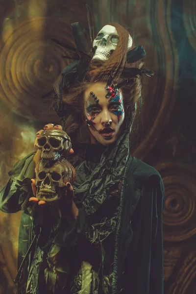 Junge Hexe mit Totenkopf. Helles Make-up und Smoke-Halloween-Thema. — Stockfoto