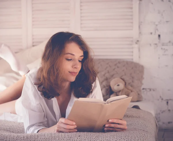 Koncepcja stylu życia i ludzi: młoda kobieta leżąca w łóżku podczas czytania — Zdjęcie stockowe