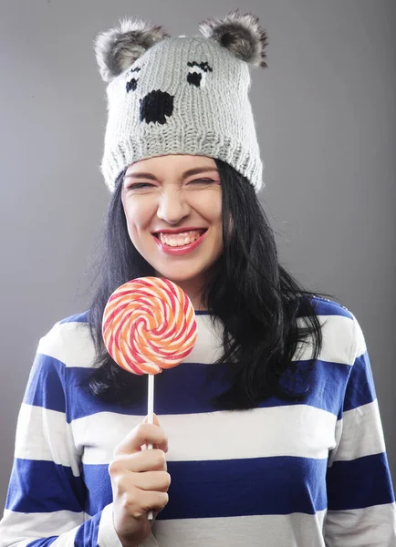 Mujer con sombrero mirando a la cámara y sosteniendo una lollipo — Foto de Stock