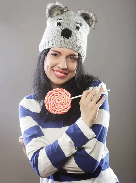 Donna che indossa cappello guardando nella fotocamera e tenendo un lecca-lecca — Foto Stock