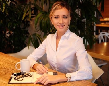 Zeki kadın fikirlerini yazıyor ve kafede kahve içiyor.