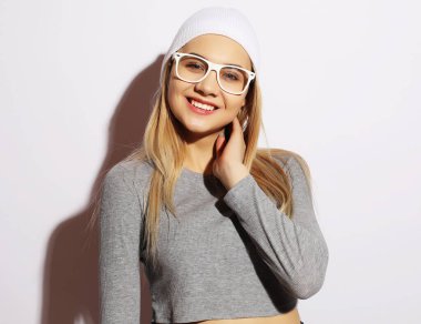 Yaşam tarzı ve insan konsepti: Beyaz gözlüklü ve şapkalı, gülümseyen genç kız..