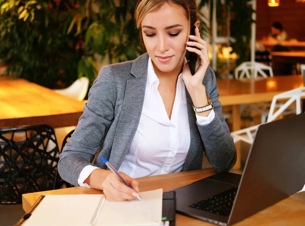 Mujer feliz utilizando el chat con el móvil y el ordenador portátil de uso — Foto de Stock