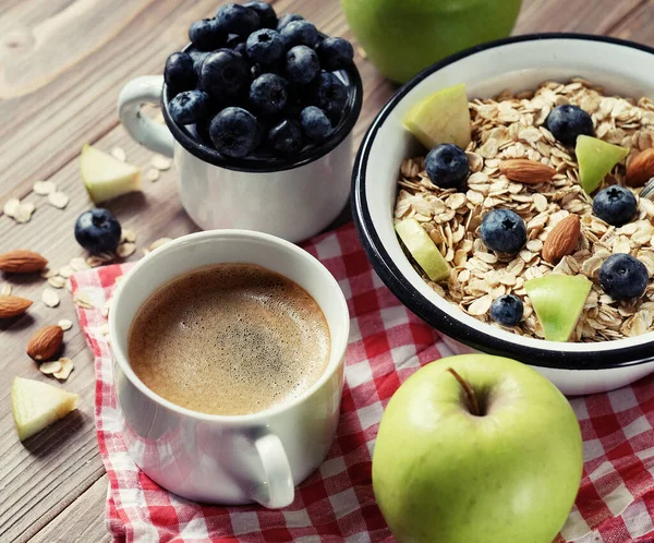 Ein gesundes Frühstück ist ein guter Start in einen neuen Tag. Haferbrei, Kaffee, Apfel, Beeren und Nüsse auf einem Holztisch. — Stockfoto