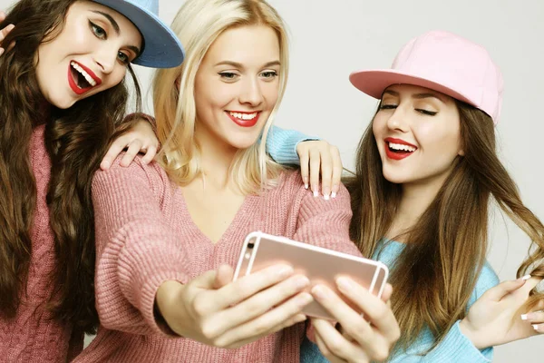 Drie gelukkige beste vriendinnen dragen truien en caps maken selfie — Stockfoto