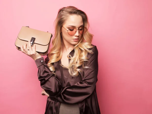 Beautiful blond woman in a blouse and pants wearing glasses, holding handbag. — Stock Photo, Image