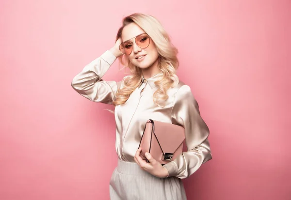 Mooie blonde vrouw in een blouse en broek met bril, met handtas. — Stockfoto