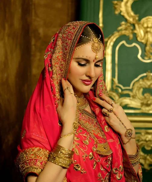 Portrait smiling of beautiful indian girl at home. Young woman model with golden jewelry set . — Stock Photo, Image