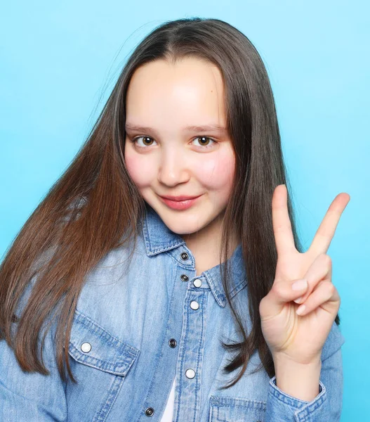 Ragazza felice guardando la fotocamera con il sorriso e mostrando segno di pace con le dita — Foto Stock