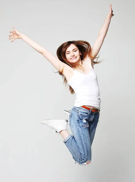 Усміхнена молода жінка стрибає в повітрі на білому тлі — стокове фото