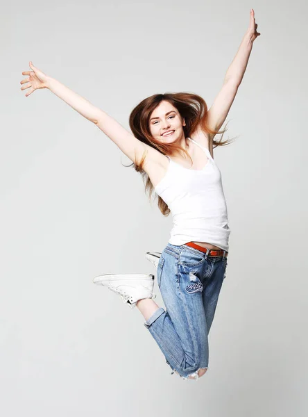 Sorrindo jovem mulher pulando no ar sobre fundo branco — Fotografia de Stock