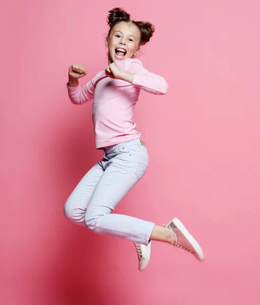 Engraçado criança menina vestido casual jumping no fundo rosa — Fotografia de Stock