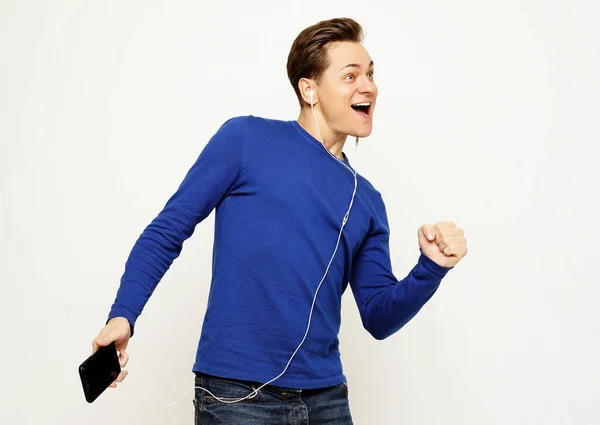 Feliz joven y elegante hombre ajustando sus auriculares y sonriendo mientras está de pie sobre fondo blanco — Foto de Stock