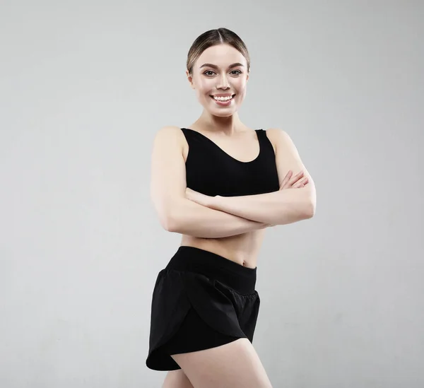 Mujer joven en ropa deportiva posando sobre un fondo blanco, concepto deportivo — Foto de Stock