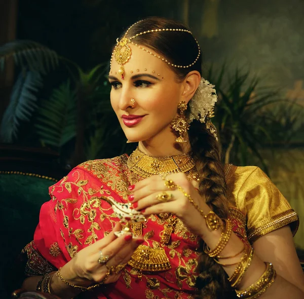 美丽的印度女孩在家里的肖像微笑。带着黄金珠宝套装的年轻女模特 . — 图库照片