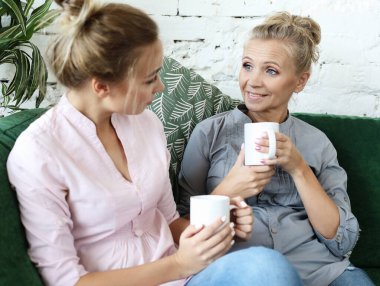 Yaşam tarzı ve insan konsepti: iki güzel kadın - anne ve kız evdeki kanepede oturuyor..