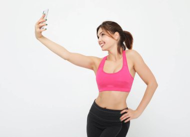 Akıllı telefonlu gülümseyen bir fitness kadınının portresi. Selfie zamanı..