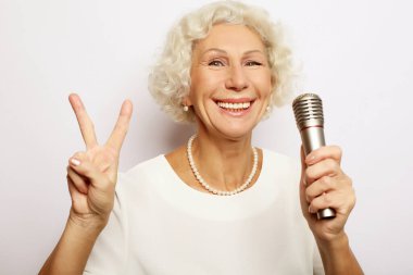 Çekici modern büyükannenin portresi mikrofon standını kaldırıp şarkı söylüyor.