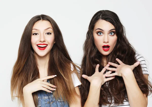 Dos amigas jóvenes divirtiéndose. Ambos haciendo caras sorprendidas. — Foto de Stock