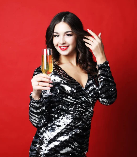 Женщина в черном вечернем платье с бокалом шампанского на красном фоне — стоковое фото