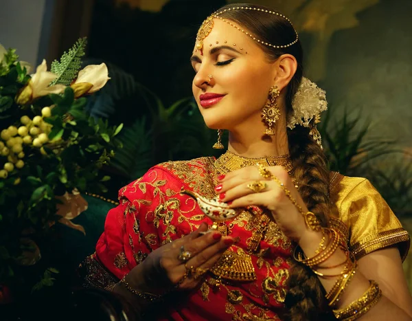 Hermosa chica india en casa. Modelo de mujer joven con conjunto de joyas de oro. Traje indio tradicional . — Foto de Stock