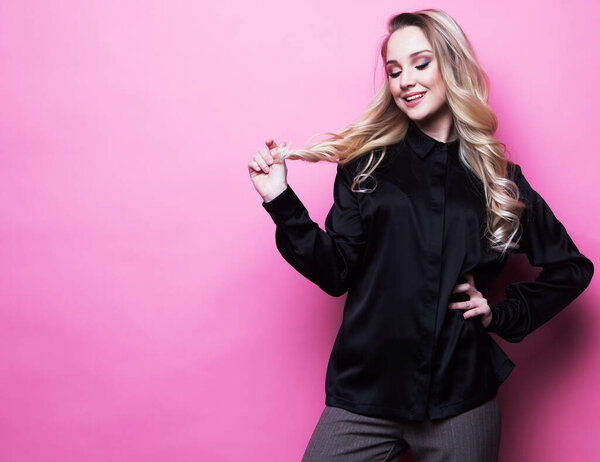 Stylish woman wearing blouse and pants posing over pink background