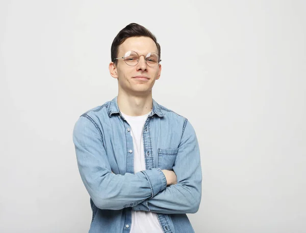 Портрет умного молодого человека в очках, стоящего на белом фоне — стоковое фото