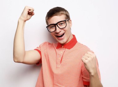 Mutlu genç yakışıklı adam el kol hareketi yapıyor ve ağzını kapalı tutuyor.