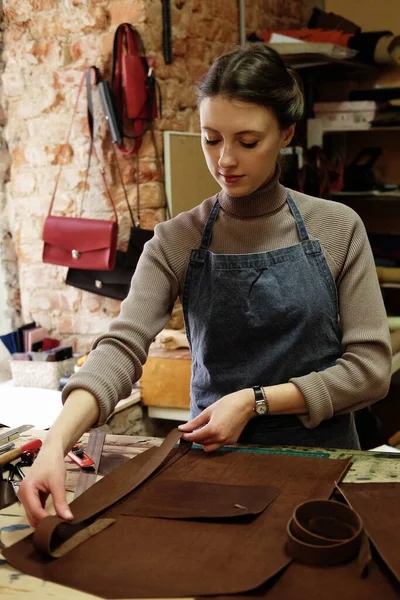 Fiatal nő dolgozik egy táska készítő stúdióban, kivágja a részleteket — Stock Fotó