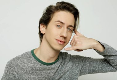 Genç çekici adam telefon işareti yapıyor.