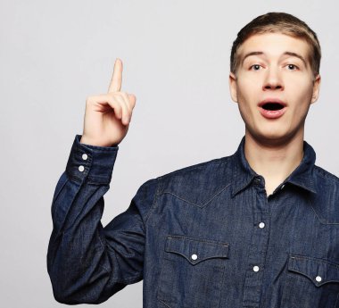 Genç adam harika bir fikir işaret ediyor, beyaz bir arka planda izole edilmiş.