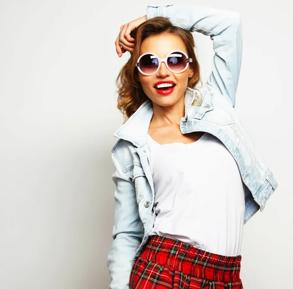 Bella giovane donna sorridente con occhiali da sole su sfondo bianco — Foto Stock