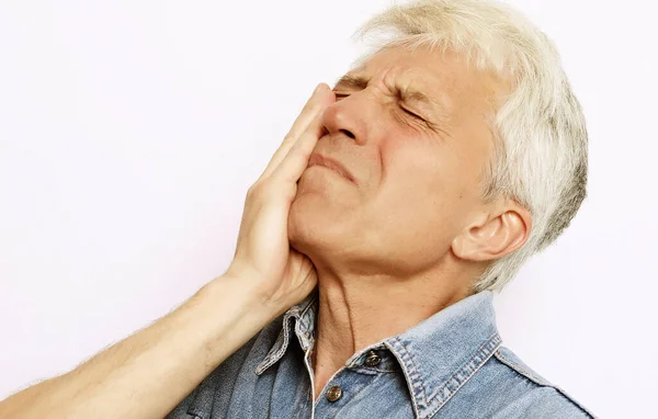 Проблеми зі здоров'ям, люди та концепція хвороби - студійний знімок нещасного старшого чоловіка, який натискає щоку, намагаючись заспокоїти зубний біль, страждаючи від болю на обличчі . — стокове фото