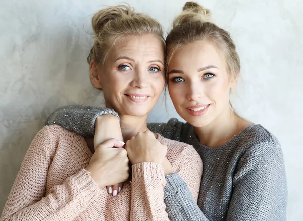 Hermosa mamá mayor y su hija adulta están abrazando, mirando a la cámara y sonriendo — Foto de Stock