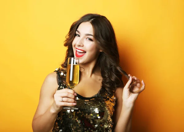 Mulher em vestido de noite segurando copo de champanhe sobre fundo amarelo — Fotografia de Stock