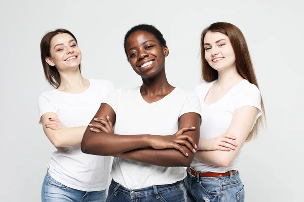 Retrato de mujeres jóvenes multirraciales de pie juntas y sonriendo a la cámara aislada sobre fondo blanco — Foto de Stock