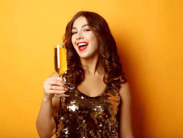 Kobieta w sukni wieczorowej trzymając szklankę szampana na żółtym tle — Zdjęcie stockowe