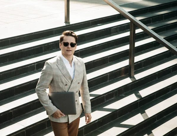 Giovane uomo d'affari sorridente trascorrere del tempo all'aperto in città, utilizzando il computer portatile sulle scale — Foto Stock