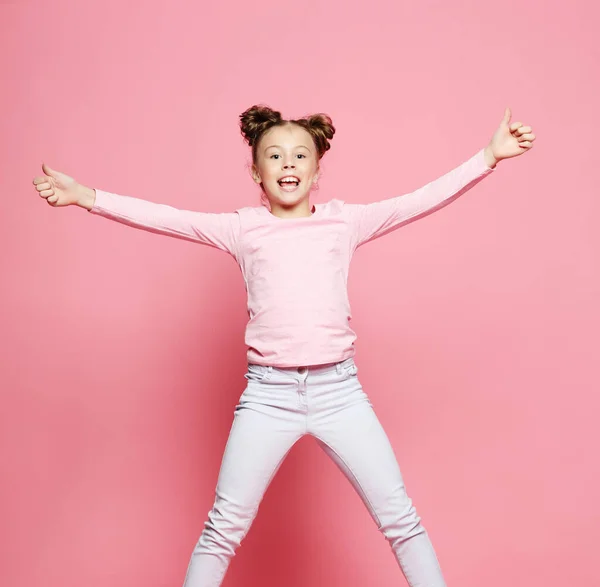 Engraçado criança menina vestido casual jumping no fundo rosa — Fotografia de Stock