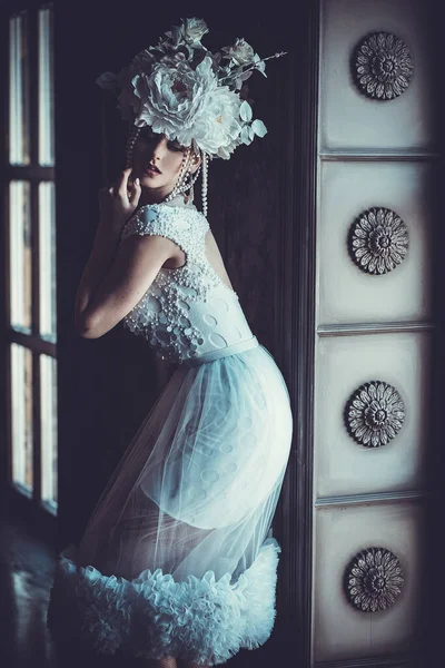 Bela jovem morena noiva vestindo branco vestido e coroa de flores senta-se em uma cadeira . — Fotografia de Stock