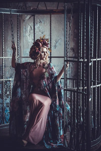 Junge blonde Frau mit Blumen im Palast. Luxuriöse Mode stilvolle Mädchen im Käfig. — Stockfoto