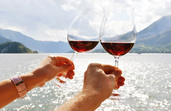 Verres à vin dans les mains contre le lac — Photo