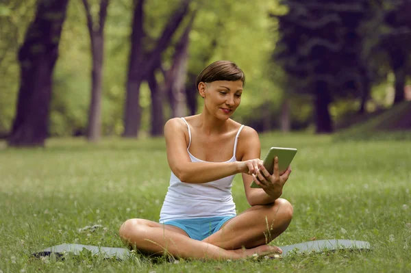 Tablet çimlere kullanan kadın. Gülümseyen. — Stok fotoğraf