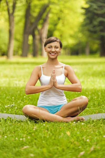 Happy young woman sitting outdoors in yoga position — Stock Photo, Image