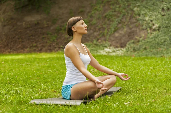 Glad ung kvinna sitter utomhus i yoga position — Stockfoto
