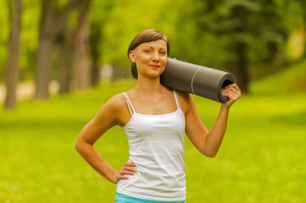 Beautiful woman with a yoga mat outdoors. — Stock Photo, Image