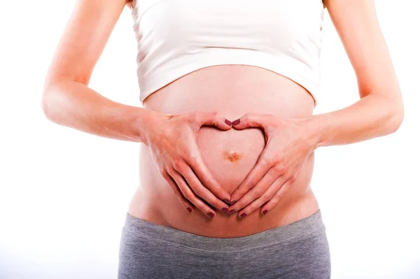 임신한 여 자가 그녀의 아기 부에 심장 모양에 그녀의 손을 잡고 — 스톡 사진