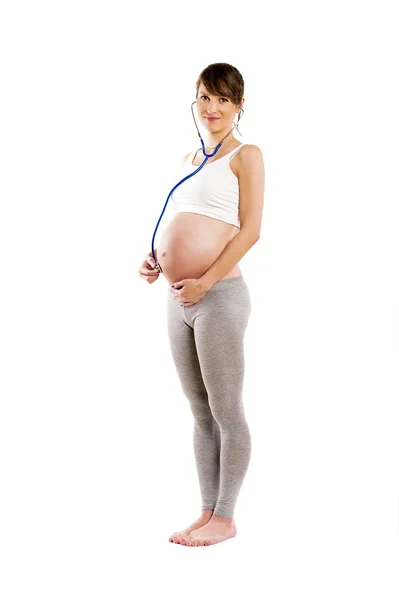 Mujer embarazada escuchar con estetoscopio a su bebé. Vientre embarazada. — Foto de Stock