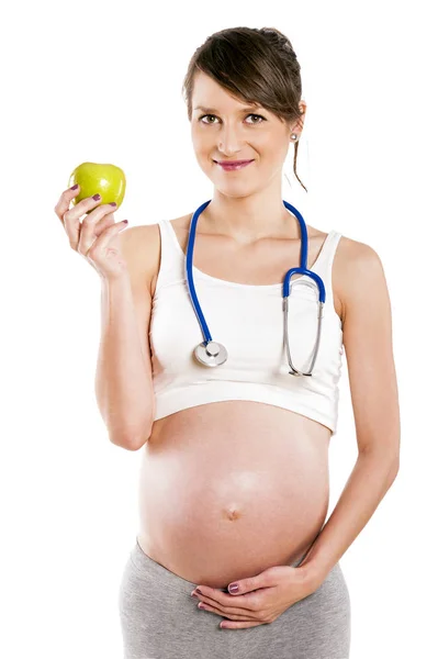 Gravid kvinna med stetoskop och äpple. Gravid mage isolat — Stockfoto