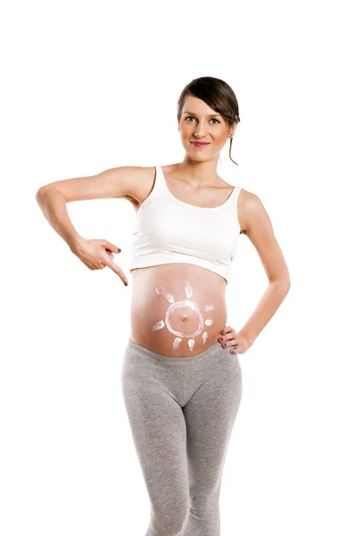 Mujer embarazada con sol crema en el vientre, aislado sobre la espalda blanca — Foto de Stock